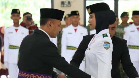 Acara Pengukuhan Paskibraka di Kota Tasikmalaya INILAHNEWS.ID - Pada Kamis, 15 Agustus 2024, Gedung Juang 45 Kota Tasikmalaya menjadi lokasi pengukuhan 35 anggota Pasukan Pengibar Bendera Pusaka (Paskibraka) tingkat Kota Tasikmalaya untuk tahun 2024. Acara tersebut dihadiri oleh Sekretaris Daerah Kota Tasikmalaya, unsur Forkopimda, anggota Purna Paskibara Indonesia (PPI) Kota Tasikmalaya, serta berbagai tamu undangan lainnya. Dalam Sambutannya Sekda Kota Tasikmalaya Drs. Asep Goparullah, M.Pd menyampaikan ucapan selamat kepada seluruh anggota Paskibraka yang telah dikukuhkan dan berpesan untuk menjaga kekompakan dan Kesehatan, karena para anggota Paskibraka ini akan menunaikan tugas yang begitu mulia untuk mengibarkan dan menurunkan bendera merah putih pada upacara peringatan HUT Republik Indonesia ke-79 tingkat Kota Tasikmalaya. Ia juga menyampaikan bahwa pengukuhan yang dilaksanakan pada hari ini merupakan langkah awal dari perjuangan para anggota Paskibraka. Bendera yang dibawa adalah simbol negara, tidak hanya sekedar seremonial saja, tetapi juga ungkapan rasa cinta tanah air. jiwa nasionalisme, patriotisme, kepeloporan serta kepemimpinan yang terbentuk selama proses latihan agar senantiasa dijadikan kepribadian yang diimplementasikan dalam kehidupan sehari-hari. Karenanya Ia berharap Paskibraka Kota Tasikmalaya mampu memberikan energi positif bagi generasi muda lainnya serta memberikan manfaat kepada masyarakat.